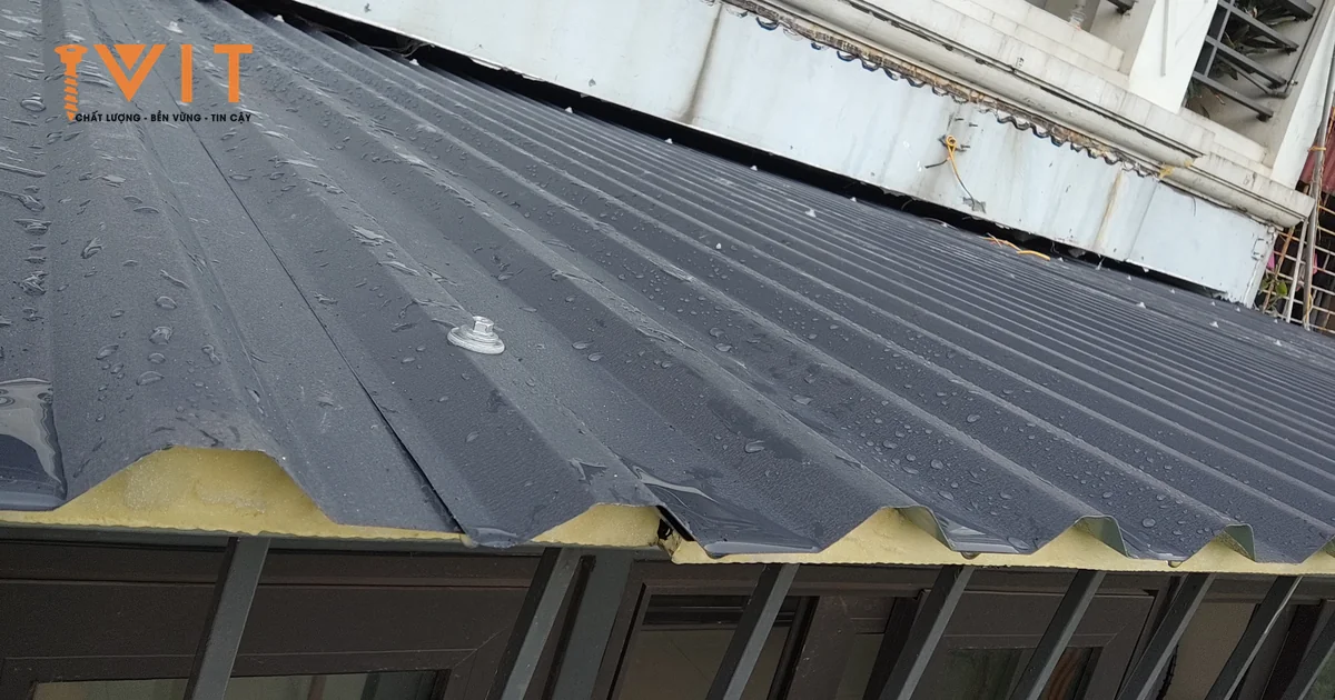 Đầu vít kèm long đệm bắt trên đỉnh sóng tấm tôn xốp màu xám, mặt tôn quanh chân vít còn phẳng