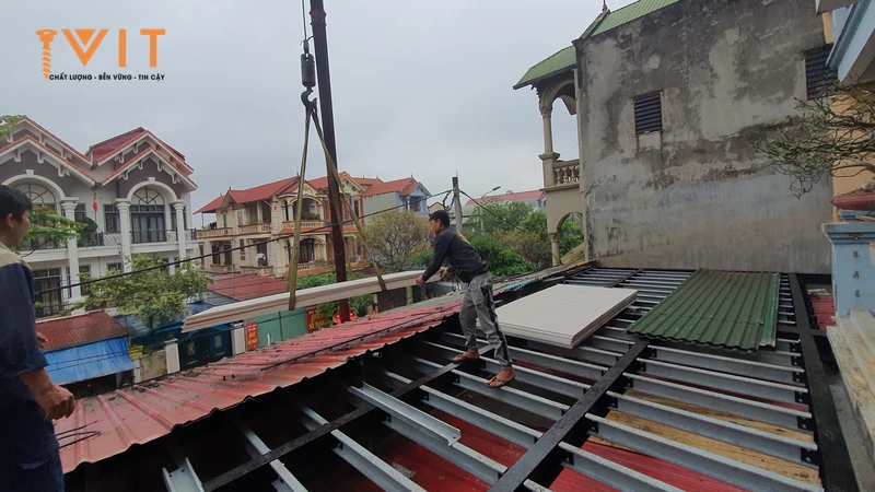 Hệ xà gồ thép của kết cấu đỡ mái lộ ra khi thợ đang lợp tấm tôn trên mái nhà dân