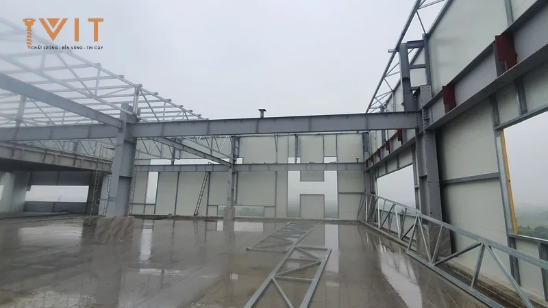 Khung kèo thép nhà xưởng tiền chế với vách panel đã lắp, mái chưa lợp và sàn bê tông còn ướt