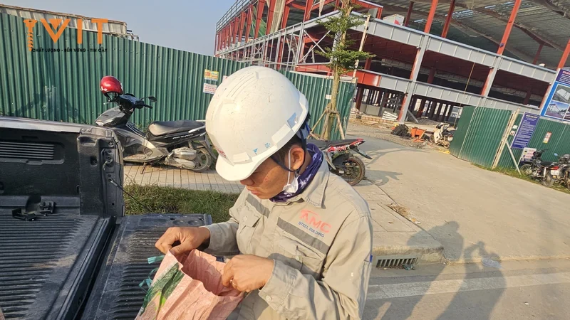 Kỹ sư đội mũ bảo hộ mở bao vật tư trên thùng xe bán tải tại công trường nhà xưởng khung thép