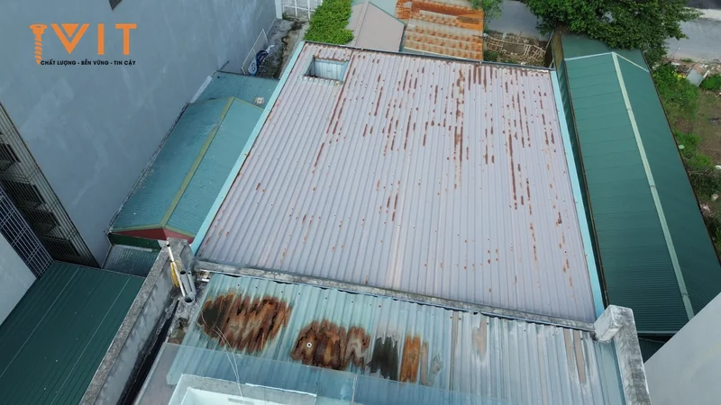 Mái tôn cũ rỉ sét loang lổ nhìn từ trên cao, minh họa ăn mòn khi mái chịu ẩm lâu ngày