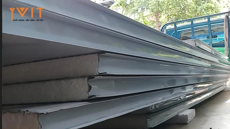 Chồng tấm panel cách nhiệt lõi xốp, mặt tôn xám bạc, xếp cạnh xe tải trước khi đưa tới công trình