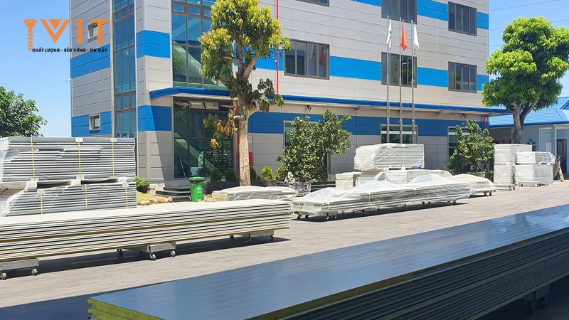 Chồng tấm panel cách nhiệt lõi xốp vàng xếp trên giá bánh xe trước tòa nhà văn phòng nhà máy