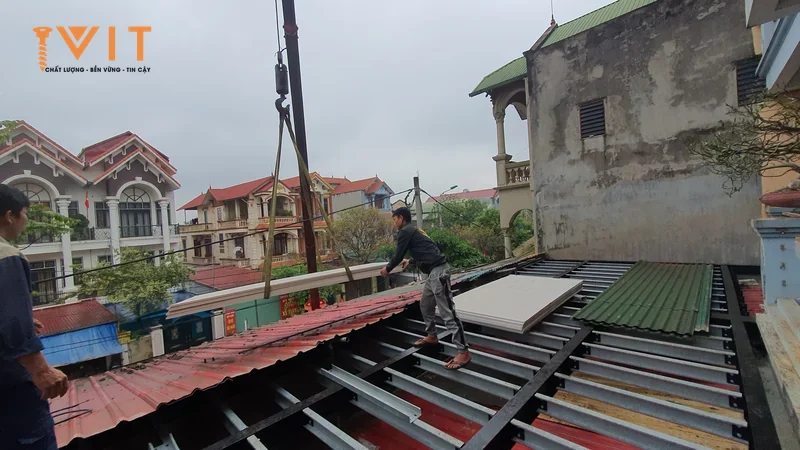 Thợ đứng trên xà gồ thép lợp tôn sóng cho nhà dân
