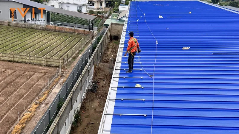 Thợ thi công đứng trên mái tôn sóng dài của công trình đang lợp
