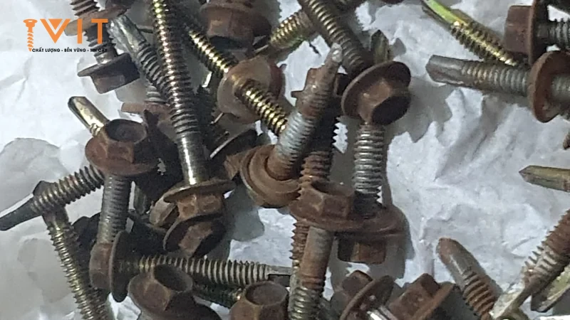 Đống vít bắn tôn đầu lục giác cũ tháo từ mái, đầu vít và long đệm rỉ nâu, thân ren loang lớp mạ