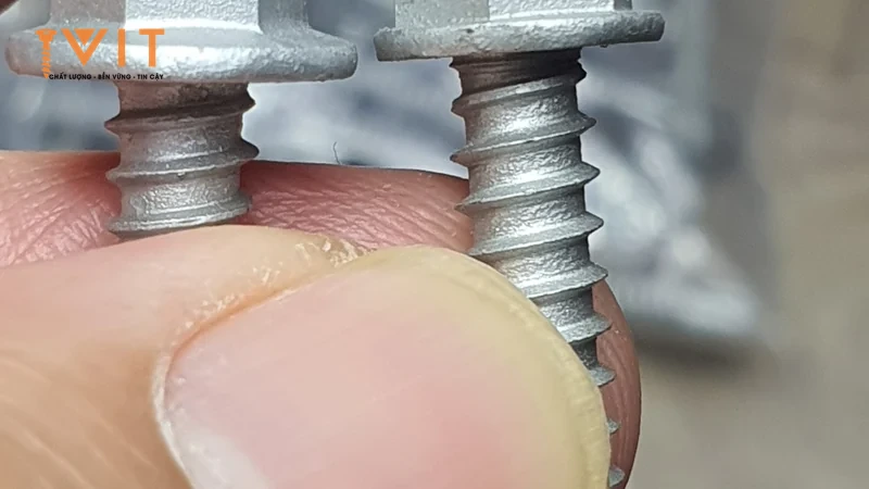 Cận cảnh đầu lục giác và phần ren của hai vít tự khoan Sheh Fung kẹp giữa hai ngón tay