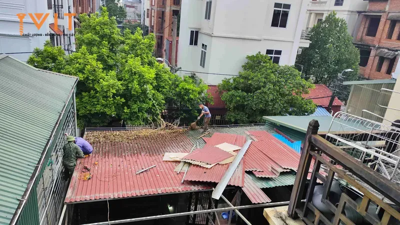 Thợ tháo dỡ và lợp lại các tấm tôn đỏ hư hỏng trên mái nhà dân, tấm cũ xếp chồng trên mái