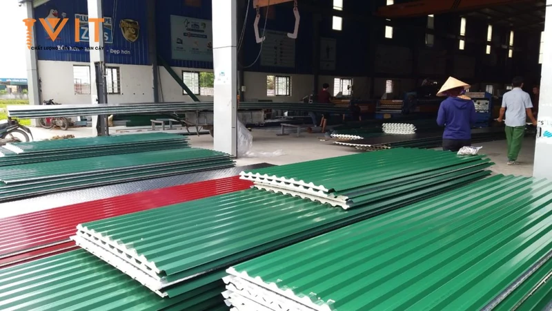 Xưởng tôn với nhiều chồng tôn xốp xanh và đỏ xếp sẵn, công nhân kiểm hàng ở phía sau